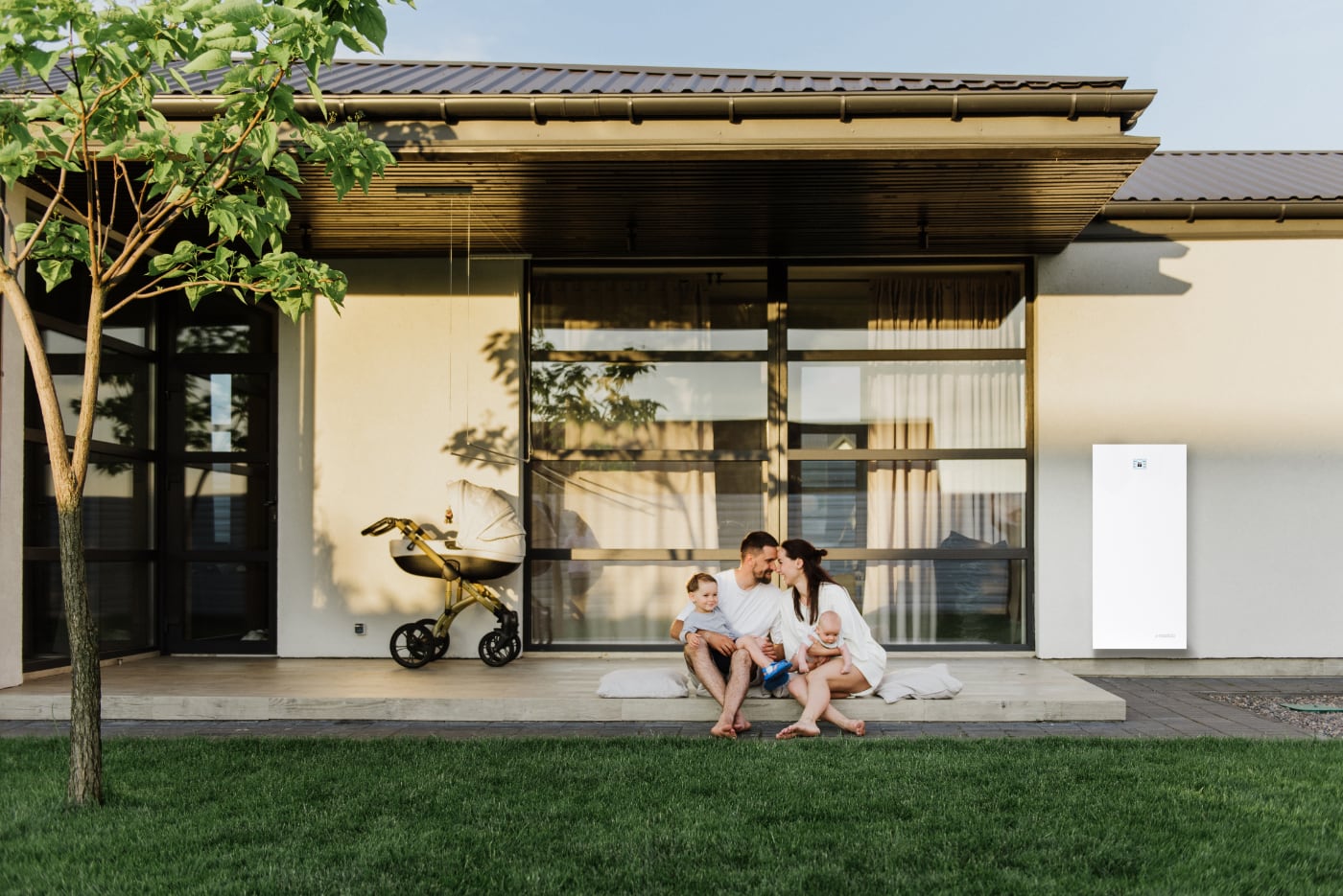 Familj som sitter på en terass, framför en villa med solceller och energisystem från emaldo